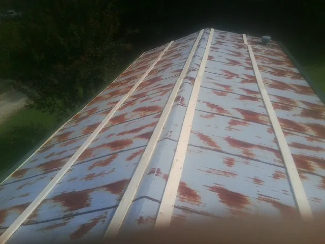 Rusted metal roof panels with new wood purlins before replacement in Shannon