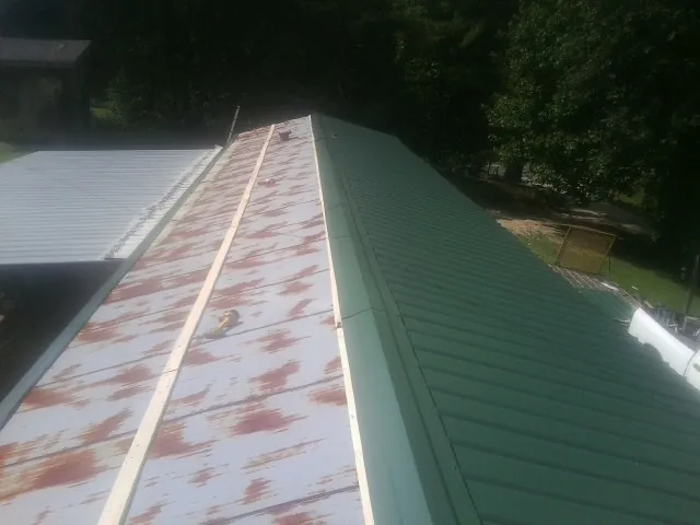 Old rusted panels beside newly installed green metal roofing — Wind Damage Roof Repair by Roofing Brothers in Shannon