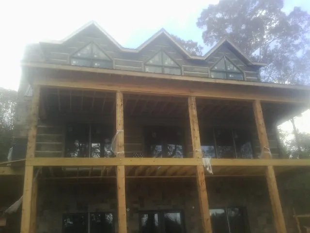 Dormers and porch framing on a large log home under construction — Roof Coating work by our crew in Shannon