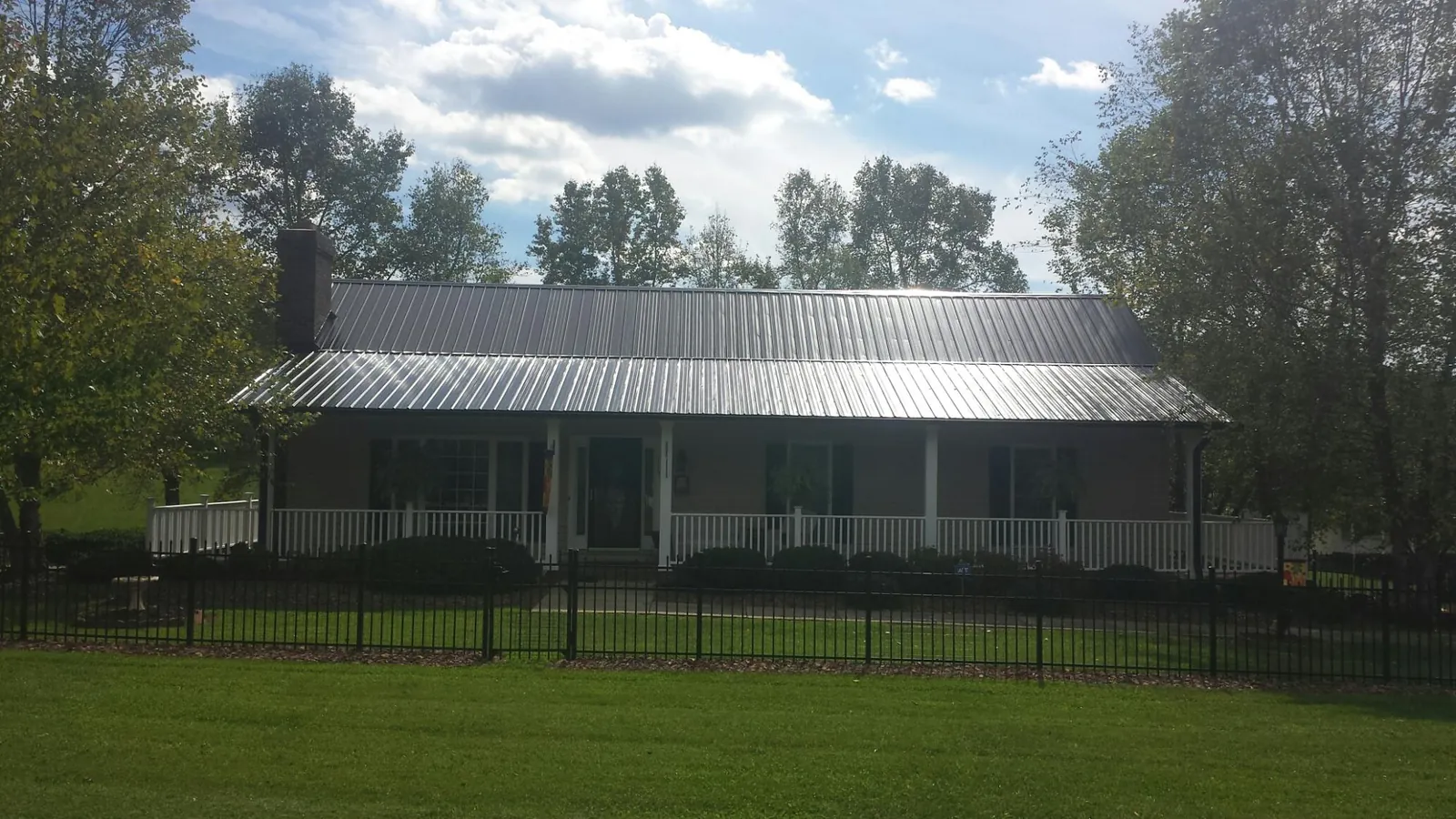Gray metal roof on a brick ranch with a full width front porch — Gutter Guard Installation work by our crew in Shannon